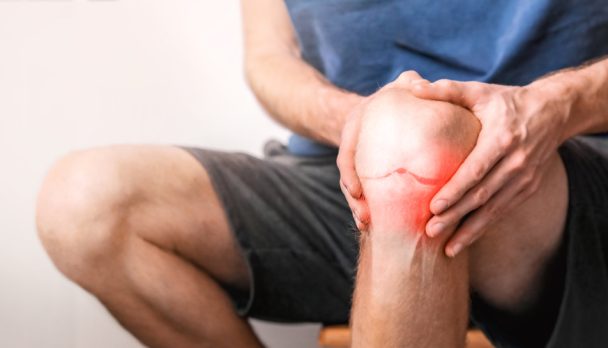 Young,Man,Suffering,From,Knee,Pain,At,Home,,Close,Up.